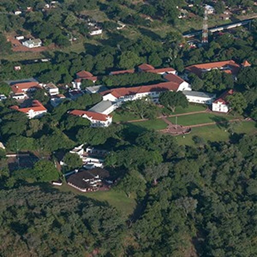 An aerial view of the hotel's red-roofed wings and lawns set among the trees of Victoria Falls town.
