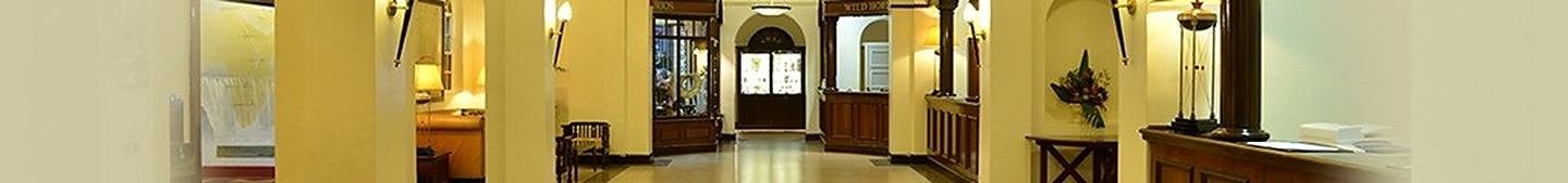 A wide view along an interior corridor of the hotel, with lamps, arches and polished floors.